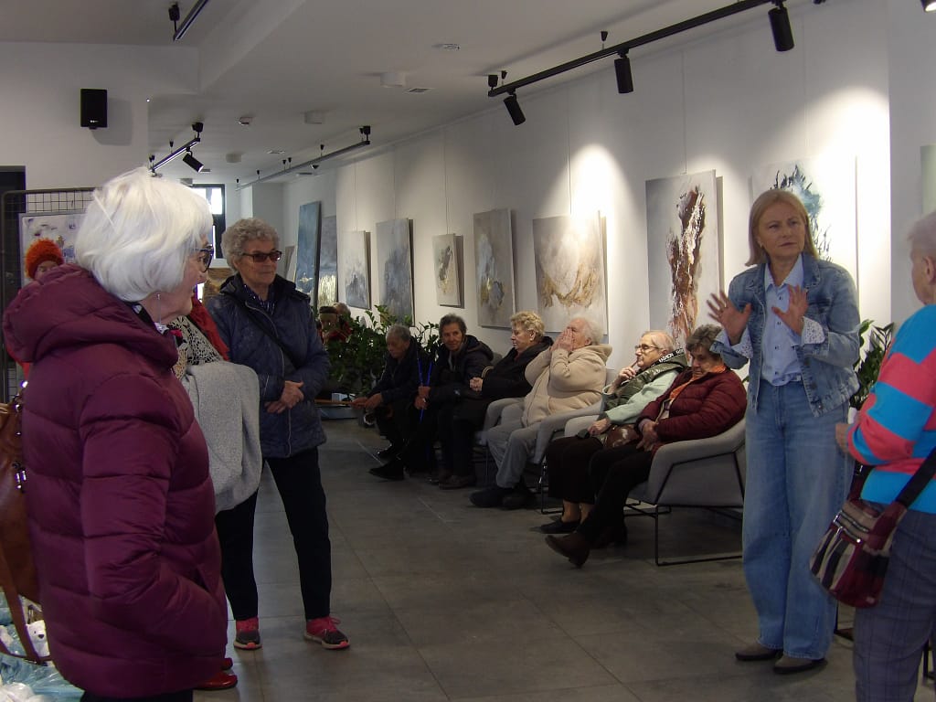 uczestnicy oglądający prace malarskie i ceramiczne