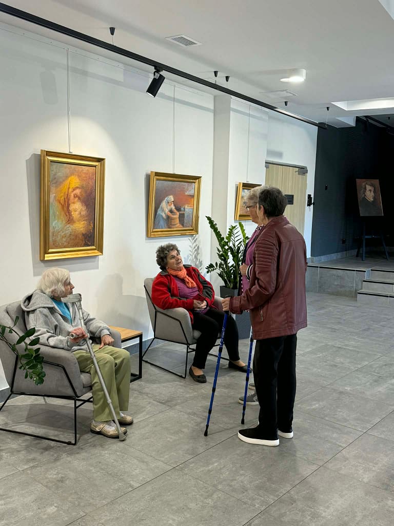 osoby oglądające obrazy namalowane przez Księdza